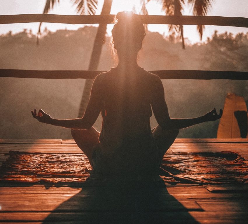 Woman meditating in Bali under a palm tree - anxiety relief