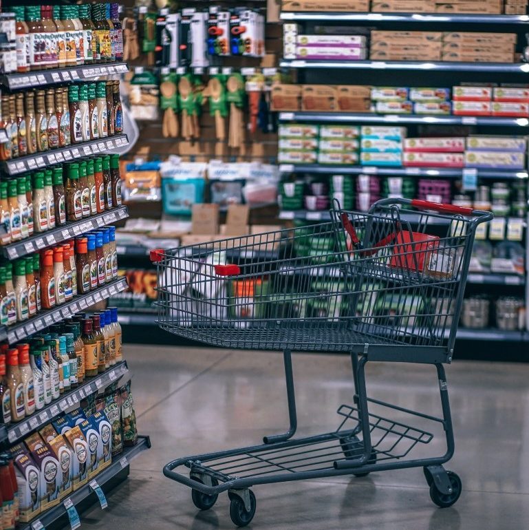 empty shopping cart in full grocery store aisle