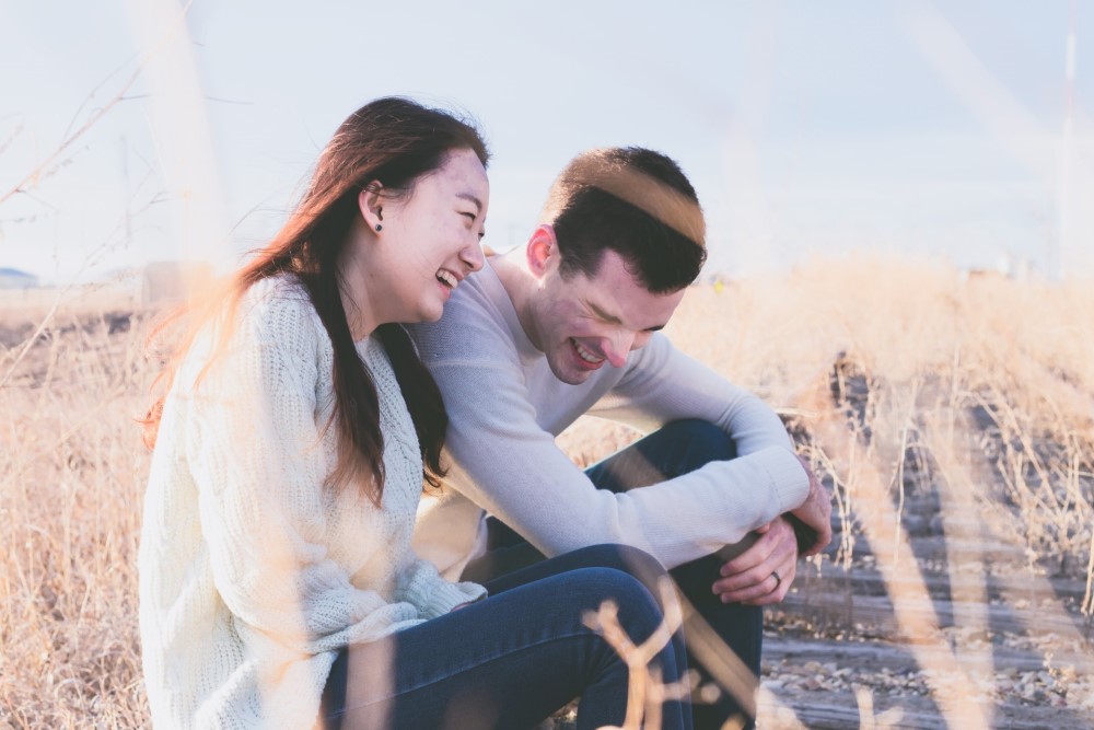 woman and man sitting in a field laughing